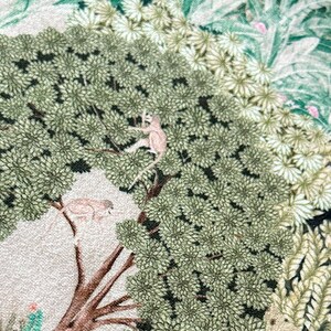 May include: A beige fabric with a green, brown, and blue floral pattern. The pattern includes a peacock with its tail feathers spread, a tree with monkeys, and a deer.
