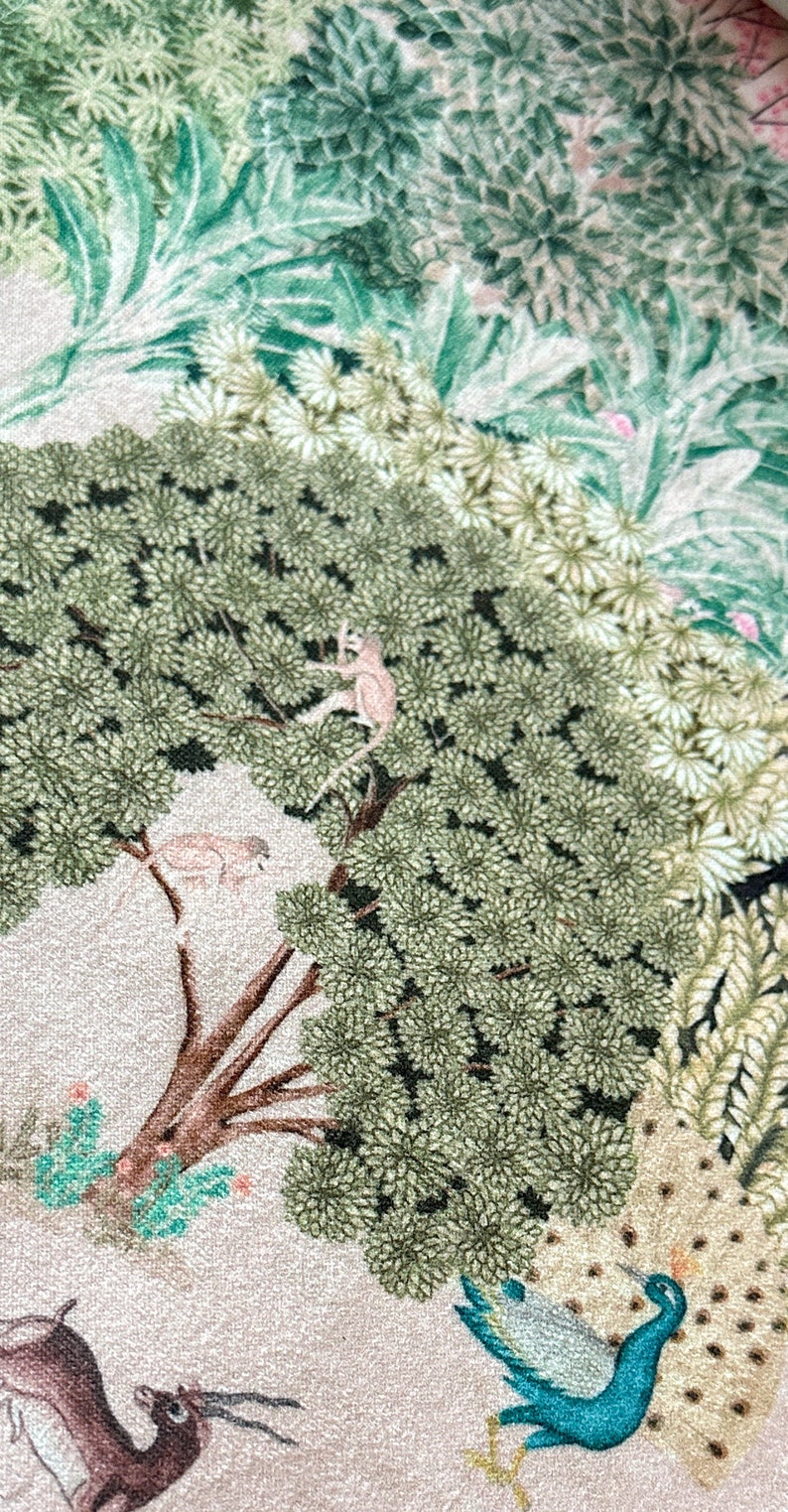 May include: A beige fabric with a green, brown, and blue floral pattern. The pattern includes a peacock with its tail feathers spread, a tree with monkeys, and a deer.