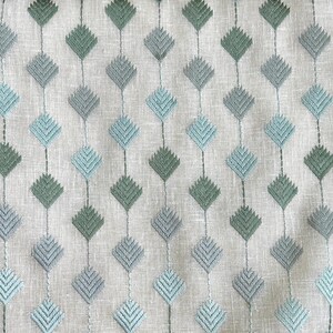 May include: A white fabric with a repeating pattern of blue and green diamond shapes. The diamonds are made of a series of small, embroidered lines.
