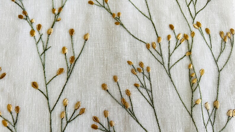 May include: White fabric with an embroidered pattern of green stems and gold leaves.