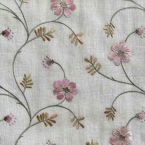 Puede incluir: Tela blanca con flores rosas bordadas y tallos verdes. Las flores tienen un aspecto delicado y vintage.
