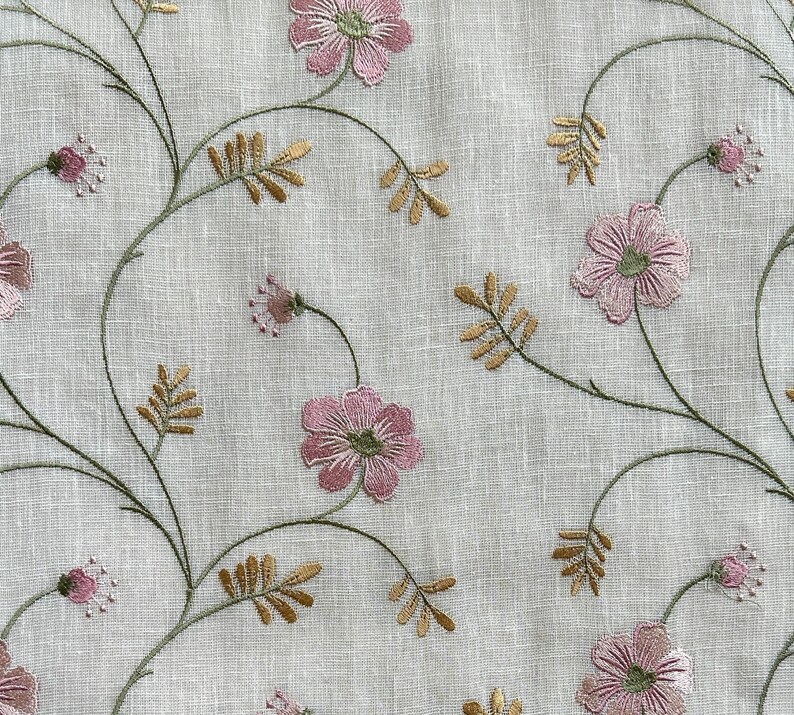 Puede incluir: Tela blanca con flores rosas bordadas y tallos verdes. Las flores tienen un aspecto delicado y vintage.