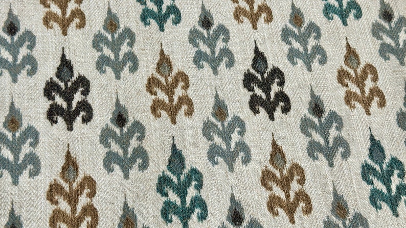 May include: A white fabric with a repeating pattern of brown, teal, and black stylized floral designs.