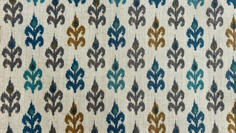 May include: A white fabric with a repeating pattern of blue, teal, brown, and gold stylized floral designs.