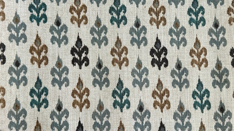 May include: A close-up of a fabric with a repeating pattern of stylized floral motifs in shades of brown, teal, and black on a white background.
