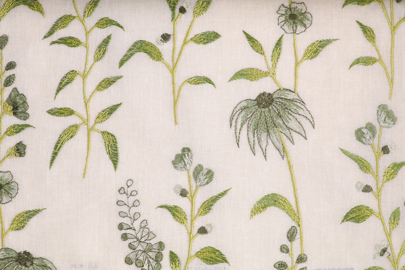 May include: White fabric with an embroidered floral pattern in shades of green. The design features delicate flowers and leaves.