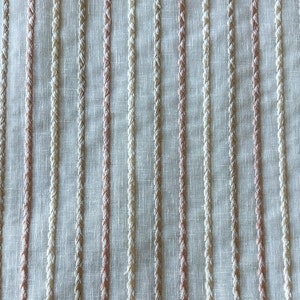 May include: White fabric with vertical stripes of beige and light pink thread.