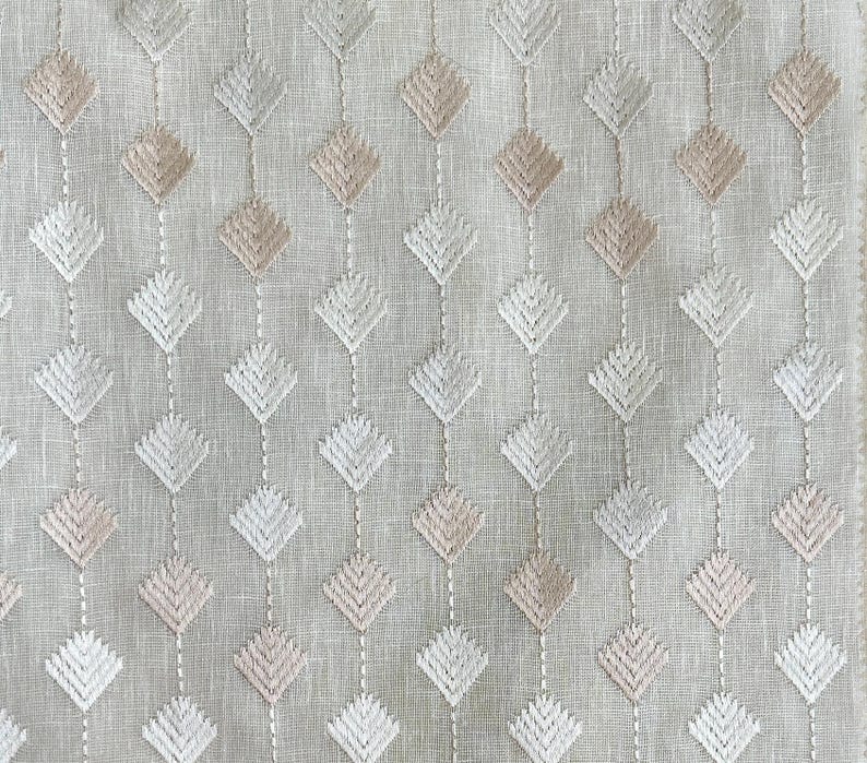Puede incluir: Una tela blanca con un sutil patr&oacute;n geom&eacute;trico de diamantes bordados en tonos beige y blanco.