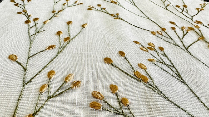 May include: White fabric with a subtle texture featuring an embroidered pattern of green stems and gold leaves.