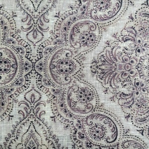 May include: A beige fabric with a paisley pattern in shades of brown and black.