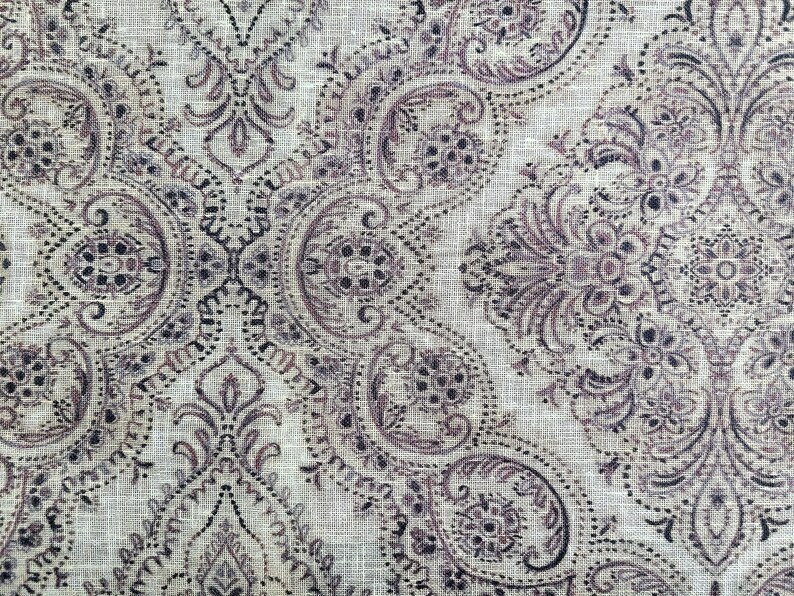 May include: A beige fabric with a paisley pattern in shades of brown and black.