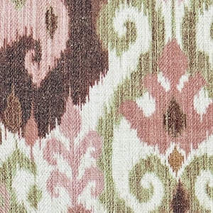 May include: Close-up of a woven fabric with an ikat design. The pattern features repeating shapes in shades of brown, pink, green, and white. The fabric has a textured appearance, suggesting a natural fibre.