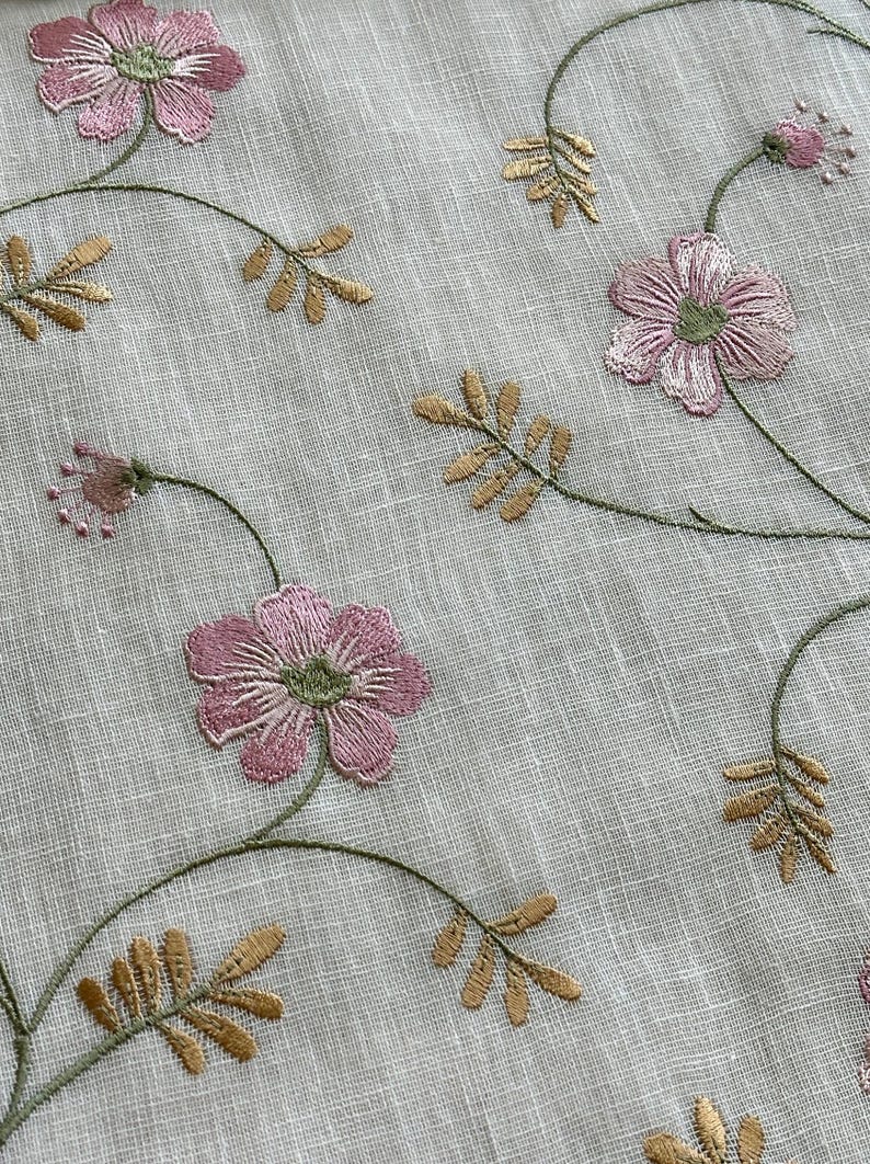 Puede incluir: Tela blanca transparente con flores rosas y hojas doradas bordadas. La tela tiene una textura sutil.