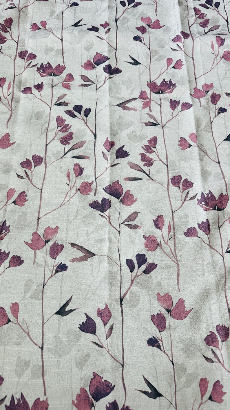 May include: A white fabric with a repeating pattern of purple and pink floral sprigs. The fabric has a subtle linen texture.