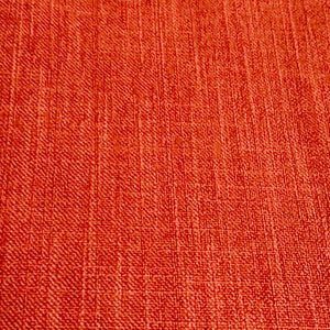 May include: A close-up of a textured, orange fabric with a subtle woven pattern.