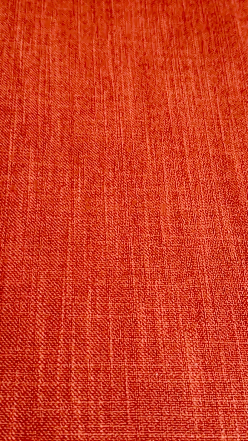 May include: A close-up of a textured, orange fabric with a subtle woven pattern.