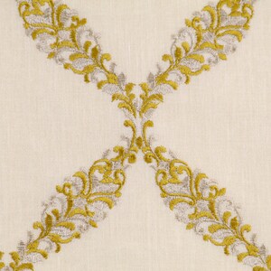 May include: A white fabric with a repeating pattern of gold and silver embroidered floral designs. The design is a series of connected swirls and leaves.