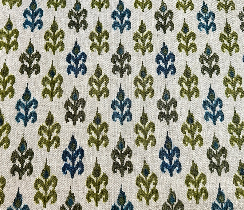 May include: A white fabric with a repeating pattern of green and blue stylized floral shapes.