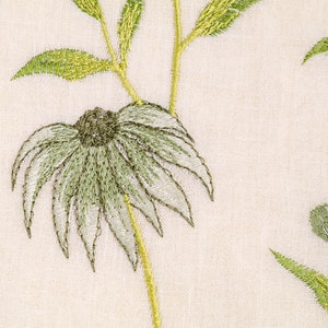 May include: A close-up of a white fabric with green embroidered flowers. The flowers have a delicate, layered design and are accented with a light green color.