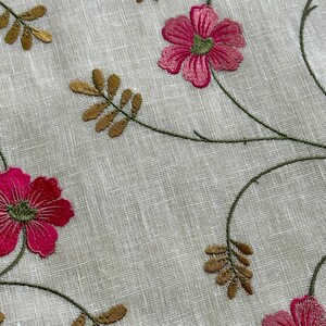 May include: White fabric with embroidered pink flowers and brown leaves. The fabric has a subtle texture.
