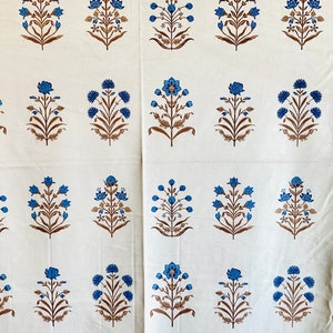 May include: White fabric with a repeating pattern of blue and brown floral designs. The fabric has a subtle texture.