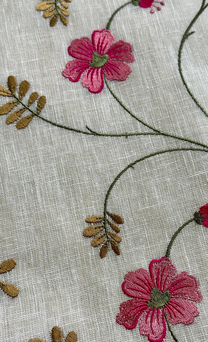 May include: Embroidered floral fabric with pink flowers and green stems on a white linen background.