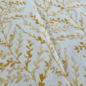 May include: White fabric with a subtle linen texture featuring a repeating pattern of gold-colored leafy branches.