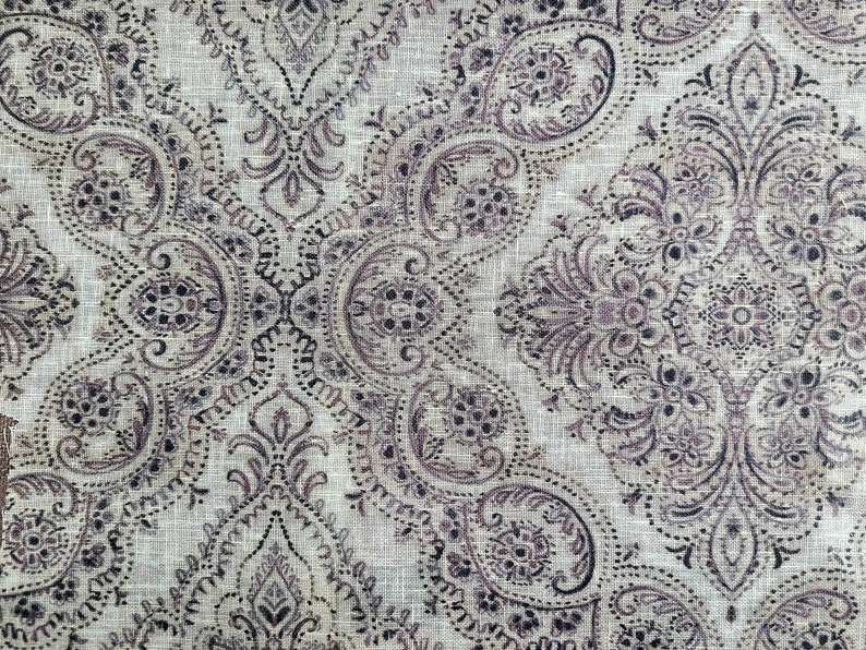 May include: A beige fabric with a brown paisley pattern. The fabric has a subtle linen texture.