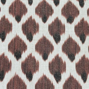 May include: A white fabric with a brown and black ikat pattern. The pattern is a repeating diamond shape with a brown center and black edges.