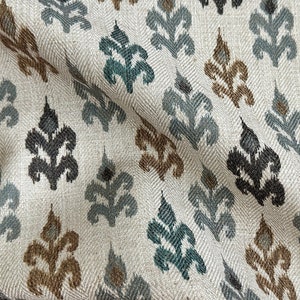 May include: A white fabric with a repeating pattern of stylized leaves in shades of teal, brown, and gray.