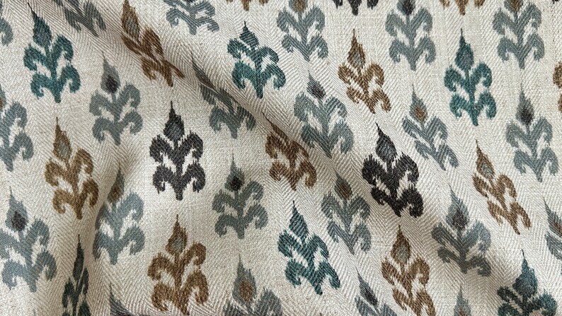 May include: A white fabric with a repeating pattern of stylized leaves in shades of teal, brown, and gray.