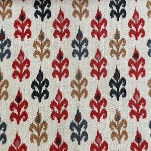 May include: A white fabric with a repeating pattern of stylized floral motifs in red, black, and brown. The pattern is a traditional ikat design.