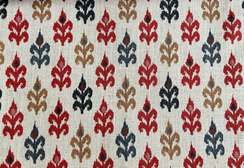 May include: A white fabric with a repeating pattern of stylized floral motifs in red, black, and brown. The pattern is a traditional ikat design.