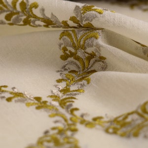 May include: White fabric with a repeating pattern of gold and silver embroidered floral designs.