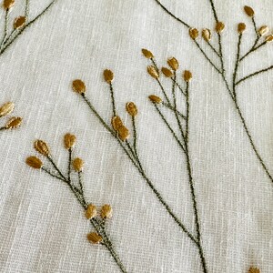 May include: White fabric with a delicate embroidered design of green stems and gold leaves.
