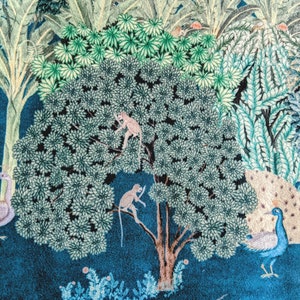 May include: A blue and green patterned fabric with a large tree in the center. The tree has two monkeys climbing on it. There is a peacock on the right side of the image and a deer on the bottom.