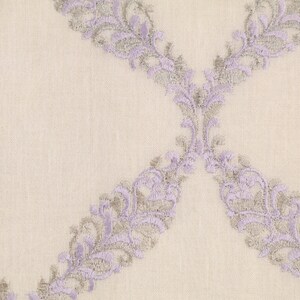 May include: A close-up of a white fabric with a delicate lavender and silver embroidered pattern. The pattern features a repeating design of stylized floral motifs.