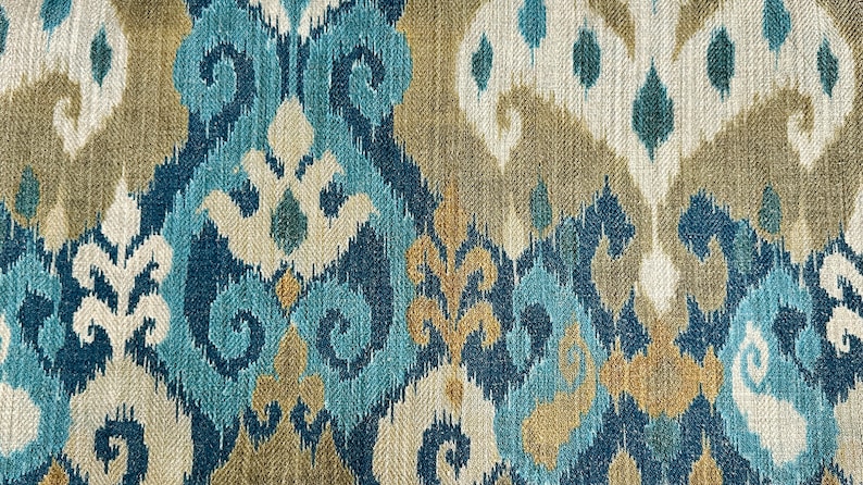 May include: Blue, beige, and white patterned fabric with an ikat design. The fabric has a woven texture.