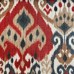 May include: Red, brown and black patterned fabric with an ikat design. The fabric has a woven texture.