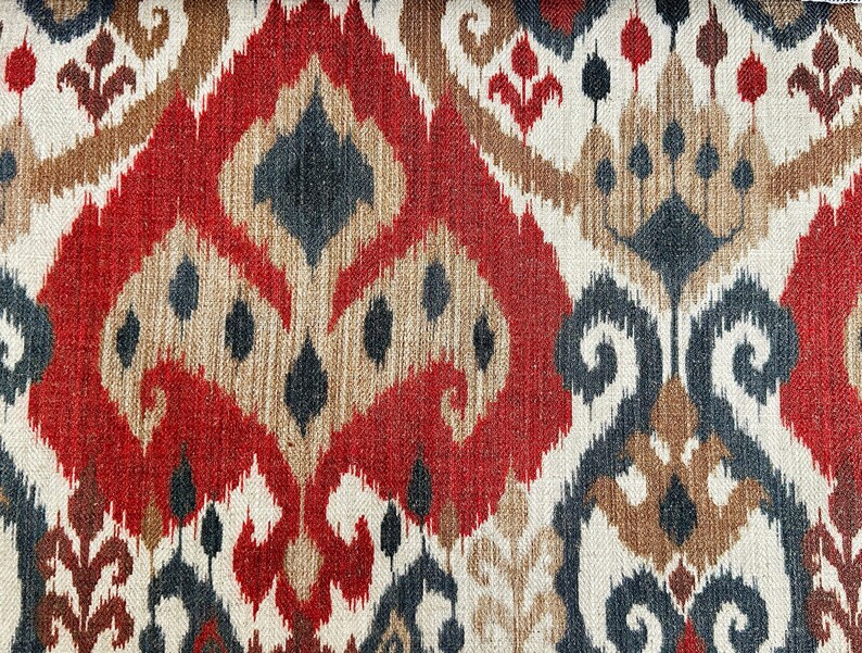 May include: Red, brown and black patterned fabric with an ikat design. The fabric has a woven texture.