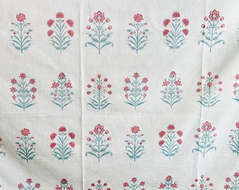 May include: White fabric with a repeating pattern of pink and blue floral designs. The fabric has a subtle texture.