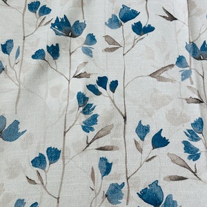 Pu&ograve; includere: Un tessuto bianco con un motivo floreale blu. I fiori sono stilizzati e assomigliano a dipinti ad acquerello.