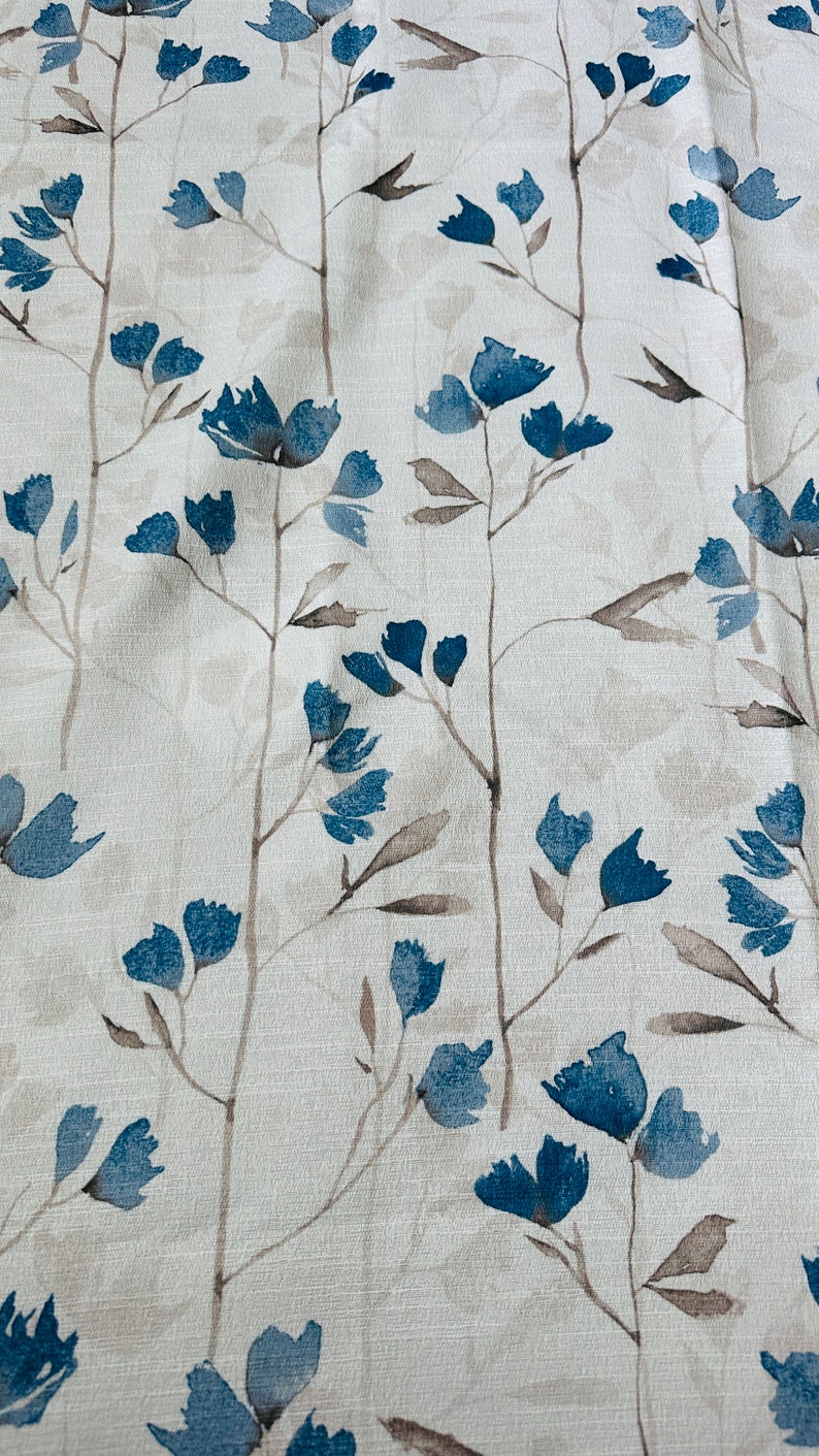 Pu&ograve; includere: Un tessuto bianco con un motivo floreale blu. I fiori sono stilizzati e assomigliano a dipinti ad acquerello.
