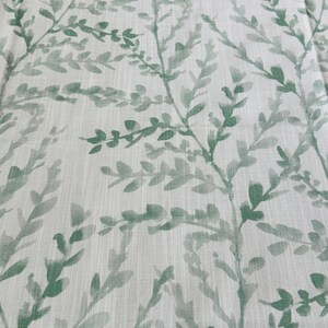 May include: A white fabric with a green leafy pattern. The leaves are painted in a watercolor style and are scattered across the fabric.