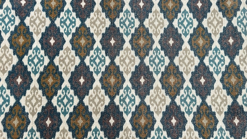 May include: A close-up of a fabric with a repeating geometric pattern. The pattern is made up of diamonds with a brown, teal, and white design. The fabric has a textured surface.