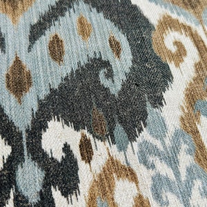 Puede incluir: Primer plano de una tela con un patr&oacute;n ikat marr&oacute;n, azul y blanco. La tela tiene una superficie texturizada y un aspecto tejido.