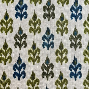 May include: A white fabric with a repeating pattern of green and blue stylized floral shapes.