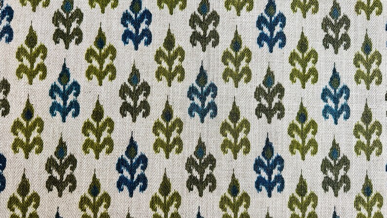 May include: A white fabric with a repeating pattern of green and blue stylized floral shapes.