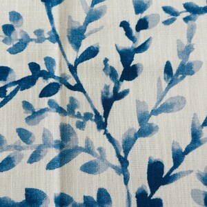 May include: Close-up of a fabric with a repeating pattern of blue watercolor-style leaves and branches against a white background. The design has a natural, botanical theme, suitable for home decor or textile applications.