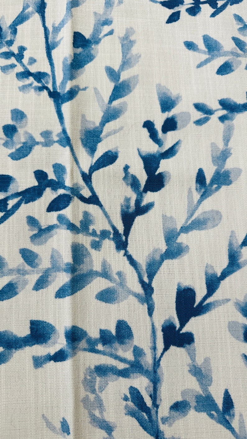 May include: Close-up of a fabric with a repeating pattern of blue watercolor-style leaves and branches against a white background. The design has a natural, botanical theme, suitable for home decor or textile applications.